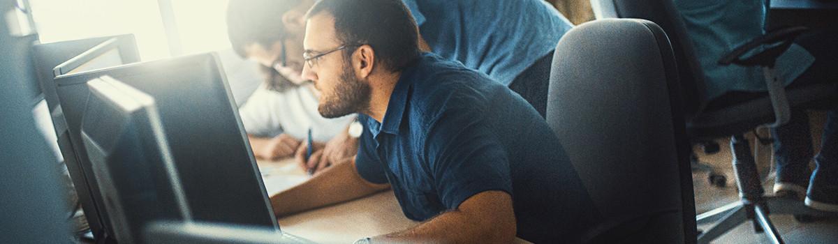 Header-Grafik Unternehmen: mehrere Personen vor Monitoren