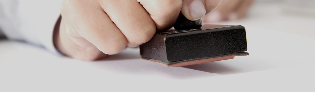 Header-Grafik Zertifizierung: Hand mit Stempel